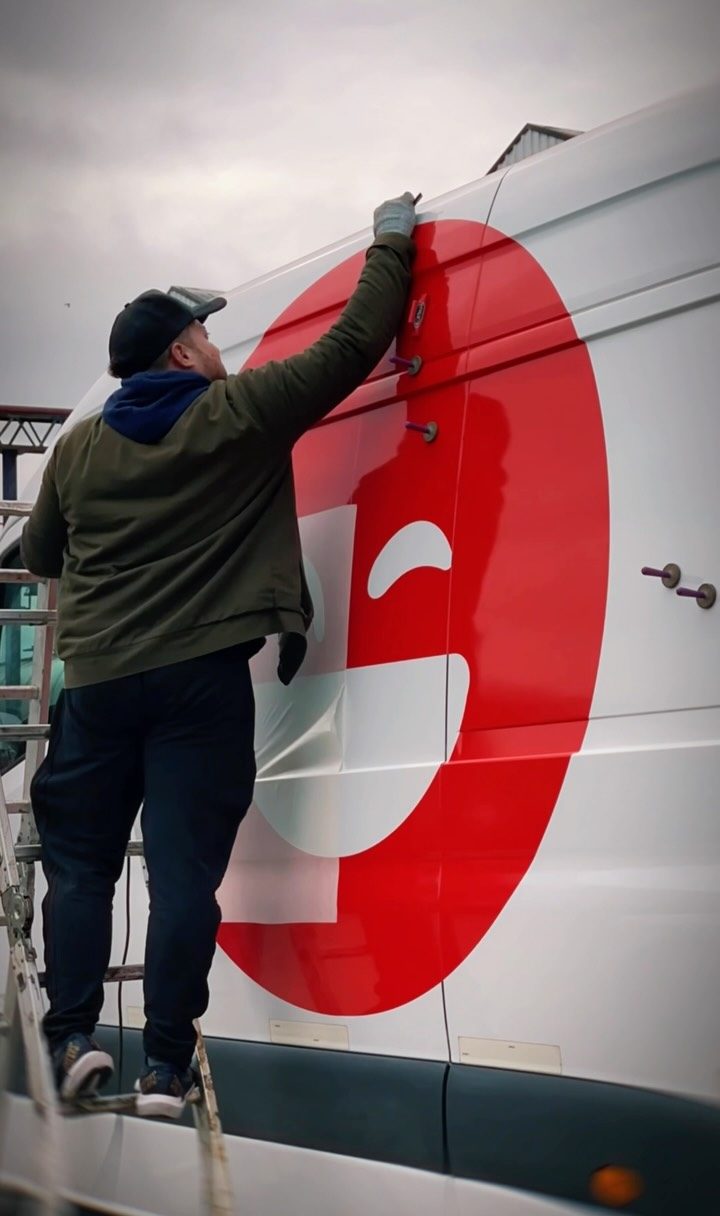 Instalador de El Detalle colocando gráfica en una van